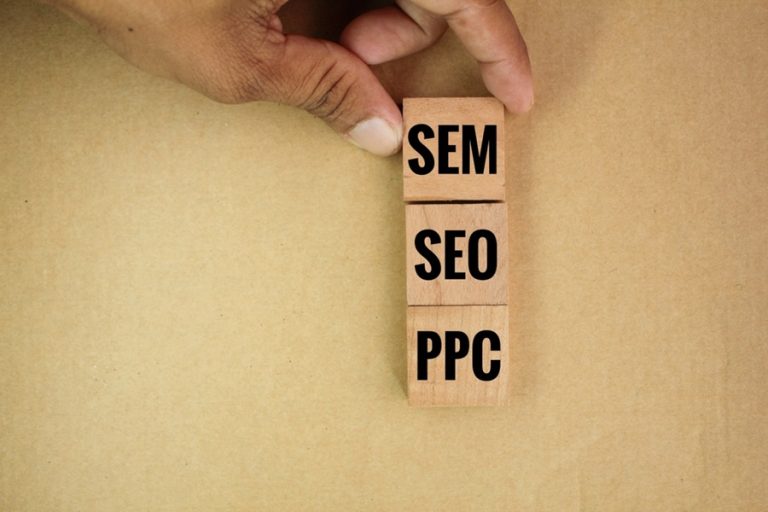 Hand stacking wooden blocks labeled SEM, SEO, and PPC representing digital marketing strategies